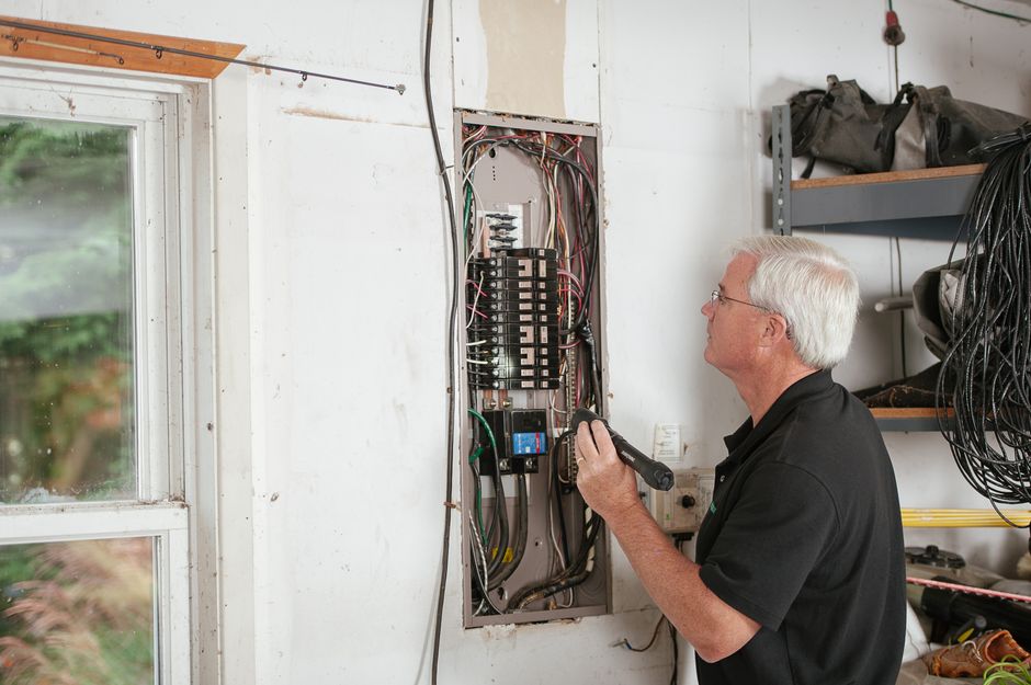 Électricien inspectant un tableau électrique à la lampe