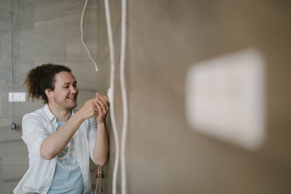 Électricien ajustant une prise murale lors d'une rénovation